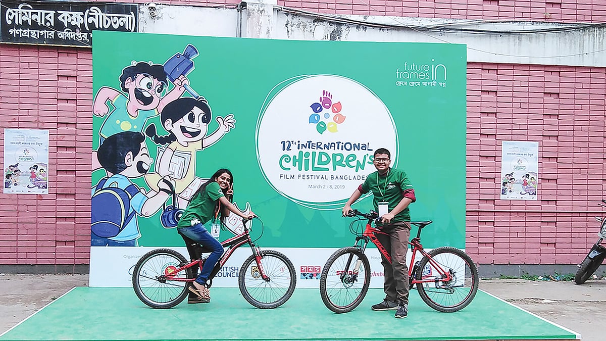 আন্তর্জাতিক শিশু চলচ্চিত্র উৎসব প্রাঙ্গণে দুই স্বেচ্ছাসেবক মেতে উঠেছেন সাইকেল নিয়ে। ছবি: প্রথম আলো