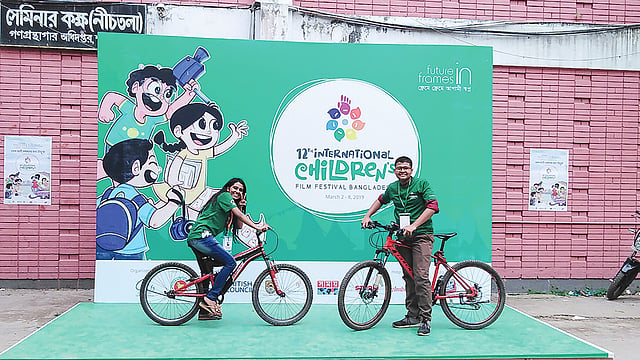 আন্তর্জাতিক শিশু চলচ্চিত্র উৎসব প্রাঙ্গণে দুই স্বেচ্ছাসেবক মেতে উঠেছেন সাইকেল নিয়ে। ছবি: প্রথম আলো