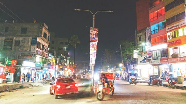 সড়ক বিভাজকের ওপর সড়কবাতিগুলো জ্বলছে না। রাস্তা আলোকিত হয়েছে আশপাশের দোকানের আলোয়। গত শুক্রবার রাতে জয়দেবপুর কেন্দ্রীয় মসজিদ রোড এলাকায়।  ছবি: প্রথম আলো