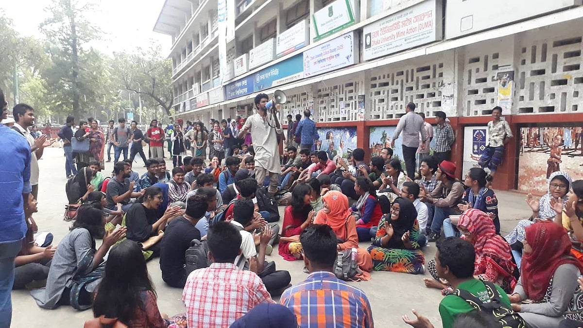 টিএসসির সামনে প্রবেশ ফটকের পাশে বসে স্লোগান দিচ্ছে শিক্ষার্থীরা। ছবি: লুৎফরজ্জামান