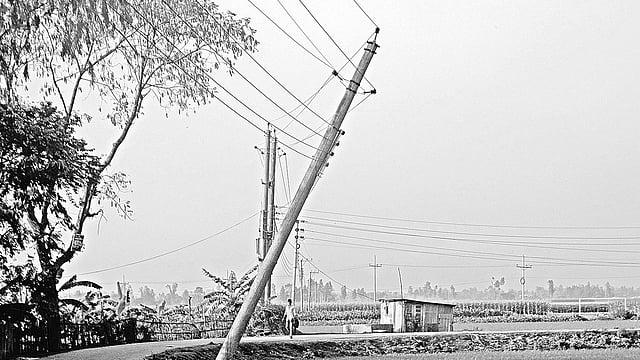 গত বছর ঝড়ে হেলে যাওয়া বৈদ্যুতিক খুঁটি। গত শুক্রবার বগুড়ার শেরপুর উপজেলার কাফুড়া পশ্চিমপাড়া গ্রামে।  ছবি: প্রথম আলো