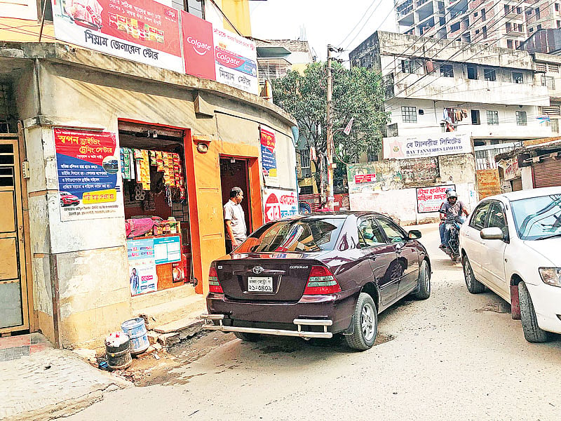 দুটি গাড়ি পাশাপাশি চললে হাঁটার জায়গা থাকে না এই সড়কে। সম্প্রতি জিগাতলার হাজারীবাগ থানা–সংলগ্ন এলাকায়।  ছবি: প্রথম আলো