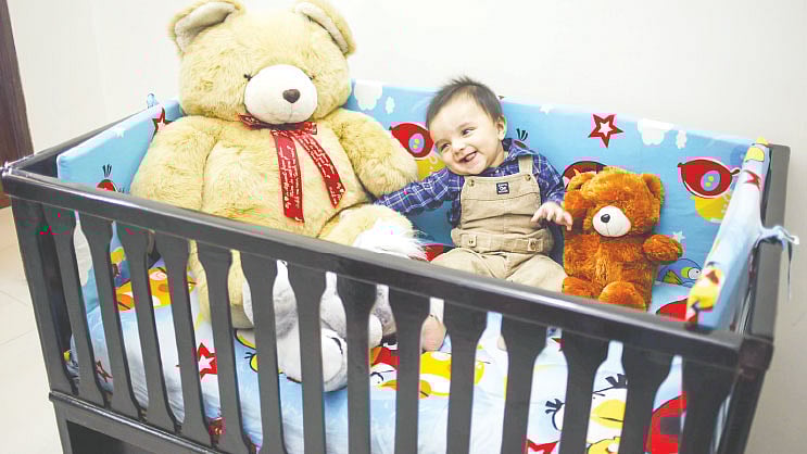 রঙিন বিছানায় হাসিখুশি শিশু। ছবি: নকশা