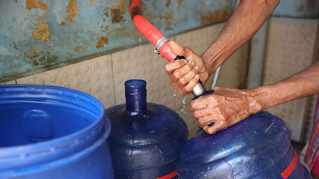 মুগদা পানির পাম্পে জারে পানি ভরছেন একজন।