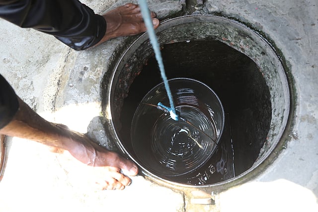 টিটিপাড়া বস্তিতে ট্যাংকের তলায় জমে থাকা পানি তুলছেন একজন।