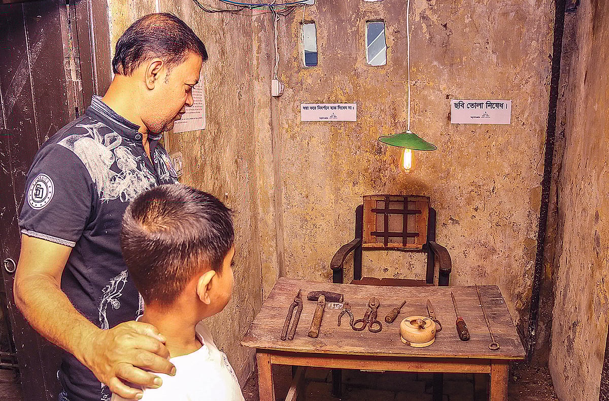 খুলনার ‘গণহত্যা-নির্যাতন আর্কাইভ জাদুঘরে’ মুক্তিযুদ্ধের ছবি ও সংরক্ষিত বিভিন্ন স্মারক শিশুসন্তানকে দেখাচ্ছেন এক বাবা। ২৪ মার্চ নগরের সাউথ সেন্ট্রাল সড়কে।  সাদ্দাম হোসেন