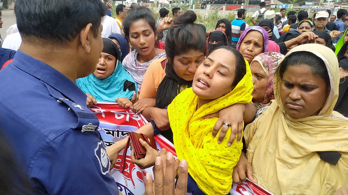 স্বামীকে হারিয়ে আহাজারি করছিলেন নিহত লিমনের স্ত্রী রূপা। তখন পুলিশ সদস্যরা তাঁকে আশ্বস্ত করছিলেন। আজ বুধবার বেলা ১১টার দিকে মাদারীপুর জেলা প্রশাসনের কার্যালয়ের সামনে। ছবি: প্রথম আলো