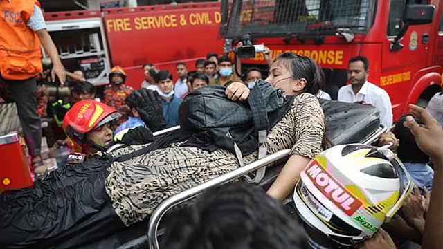 অগ্নিকাণ্ডের পর ভবনে আটকে পড়া এক নারীকে উদ্ধার করে নিয়ে আসছেন ফারায় সার্ভিসের কর্মীরা। বনানী, ঢাকা, ২৮ মার্চ। ছবি: আবদুস সালাম