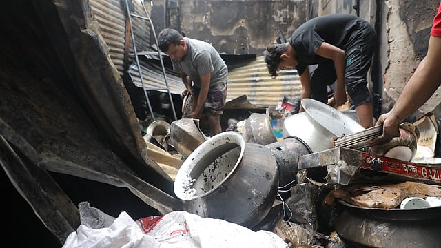 পুড়ে যাওয়া দোকানে অক্ষত কিছু অবশিষ্ট আছে কিনা খুঁজে দেখা হচ্ছে।