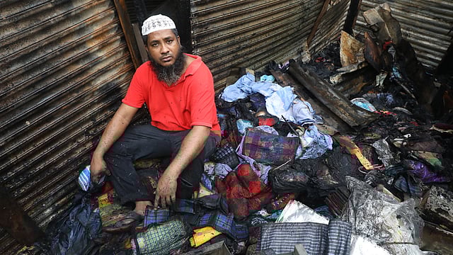সর্বস্বান্ত হয়ে পুড়ে যাওয়া দোকানেই বসে আছেন একজন।