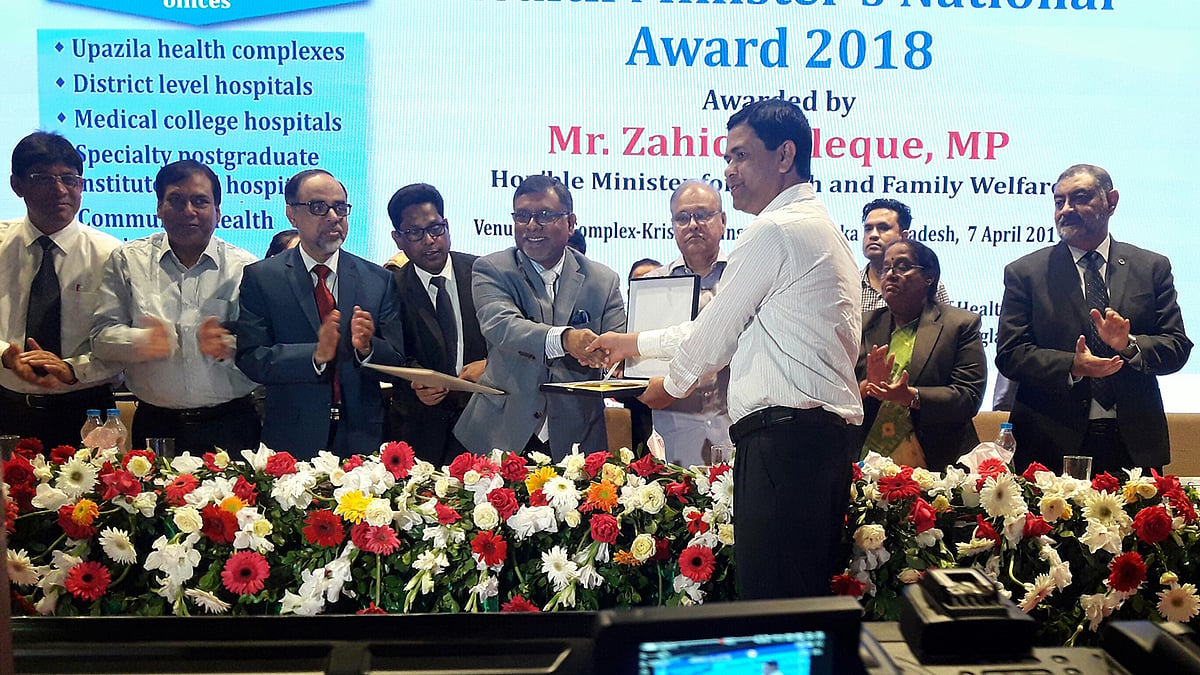 স্বাস্থ্যমন্ত্রী জাহিদ মালেকের কাছ থেকে জাতীয় পুরস্কার গ্রহণ করেন উপজেলা স্বাস্থ্য ও পরিবার পরিকল্পনা কর্মকর্তা শেখ আবু শাহীন। ছবি: সংগৃহীত
