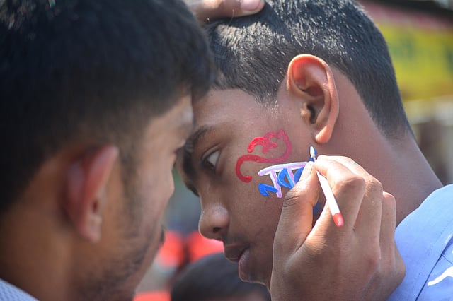 বর্ষবরণের আয়োজনে আসা শিশুরা গালে আলপনা করছে। ছবি: শিমুল তরফদার