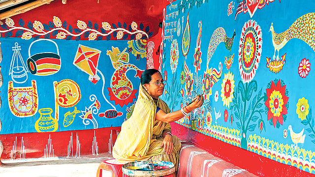 বাড়ির দেয়ালে আলপনা অাঁকছেন দেখন বালা। গত শুক্রবার সকালে চাঁপাইনবাবগঞ্জের নাচোল উপজেলার টিকইল গ্রামে।  ছবি: শহীদুল ইসলাম