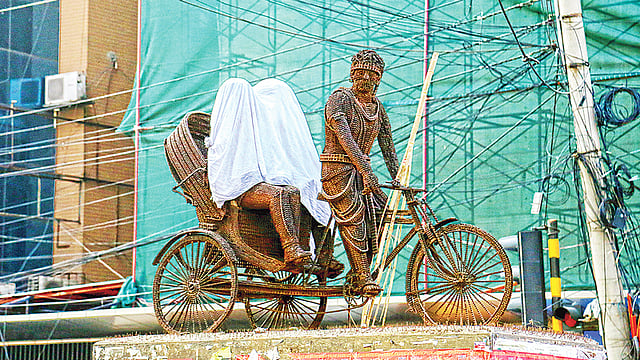 ধানমন্ডি ২৭ নম্বর মোড়ে শিল্পী মৃণাল হকের তৈরি ভাস্কর্য ‘ইস্পাতের কান্না’। এর দুই নারী আরোহীকে দুর্বৃত্তরা কাপড় দিয়ে ঢেকে দিয়েছে এবং পুরুষ রিকশাচালকের রিকশায় গেঁথে দিয়েছে বাঁশের বর্শা। গতকাল বিকেলে।  ছবি: সাবরিনা ইয়াসমীন