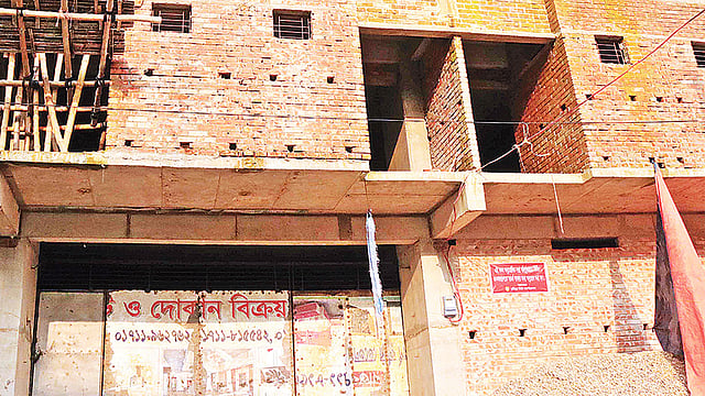অনুমোদিত নকশাবহির্ভূতভাবে নির্মিত ভবনের গায়ে সতর্কতা–সংবলিত লাল পোস্টার টানিয়ে দিয়েছে কুমিল্লা সিটি করপোরেশন। গত মঙ্গলবার নগরের বাগিচাগাঁও ফায়ার সার্ভিস সড়কে।  ছবি: প্রথম আলো