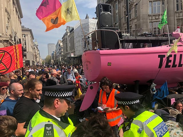 অক্সফোর্ড সার্কাস এলাকায় এক আন্দোলনকারীকে গ্রেপ্তারের প্রস্তুতি নিচ্ছে পুলিশ। সেখানে আন্দোলনকারীদের পক্ষে নজর রাখছেন একজন আইনি পর্যবেক্ষক (কমলা রঙের পোশাকে)। ছবি: তবারুকুল ইসলাম