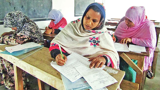 মা মাসুমা খাতুন (সামনে) এবার এইচএসসি পরীক্ষা দিচ্ছেন। গতকাল রাজশাহীর বাগাতিপাড়া ডিগ্রি কলেজ কেন্দ্রে।  ছবি: প্রথম আলো