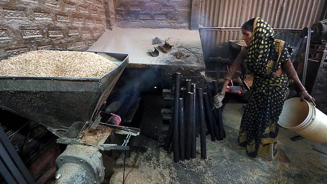 মেশিনে দেওয়া হয়েছে তুষ। অন্যদিকে বের হচ্ছে লাকড়ি