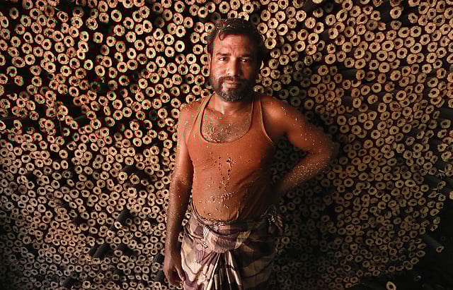 চারকোল লাকড়ির সামনে দাঁড়িয়ে কারখানার এক শ্রমিক