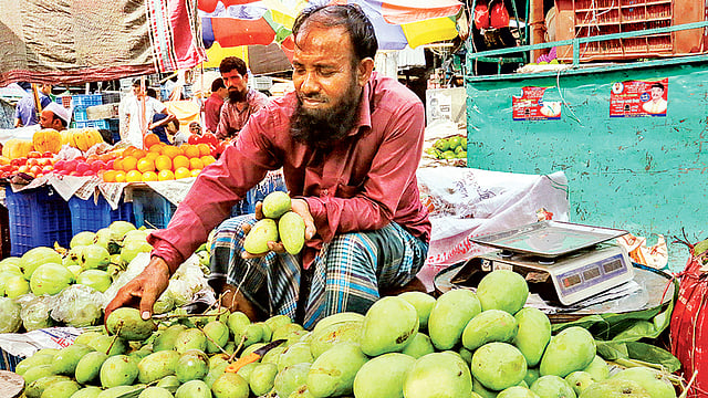 কাঁচা আম নিয়ে ক্রেতার অপেক্ষায় বিক্রেতা। গতকাল কারওয়ান বাজারে।  ছবি: প্রথম আলো