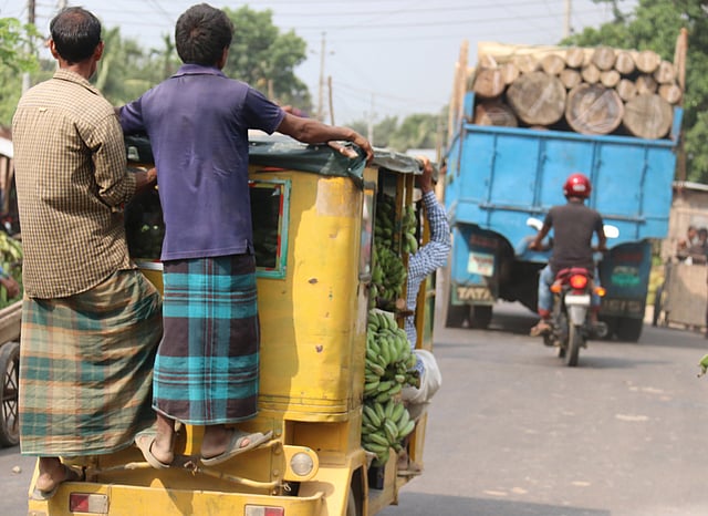 ব্যাটারিচালিত অটোরিকশার ভেতরে জায়গা নেই। মালামালে পূর্ণ সেটি। দুই যাত্রী ঝুঁকি নিয়ে পেছনে দাঁড়িয়ে গন্তব্যে যাচ্ছেন। মাটিরাঙ্গা বাজার, খাগড়াছড়ি, ২৭ এপ্রিল। ছবি: নীরব চৌধুরী