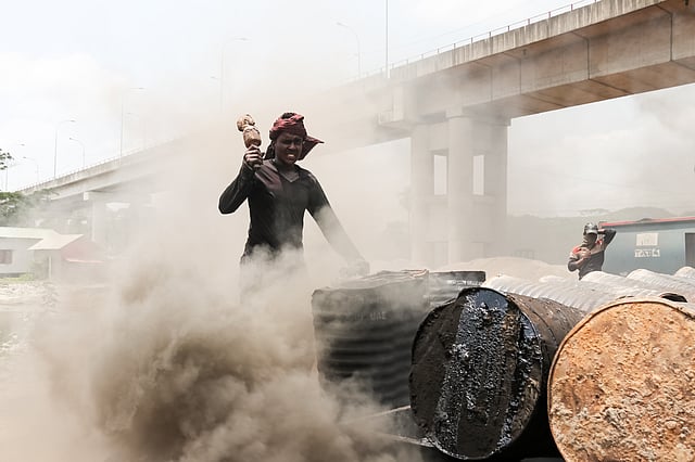 আগুনের তাপ ও কালো ধোঁয়ার মধ্যে কাজ করছেন শ্রমিকেরা। দপদপিয়া সেতু এলাকা, বরিশাল। ছবি: সাইয়ান