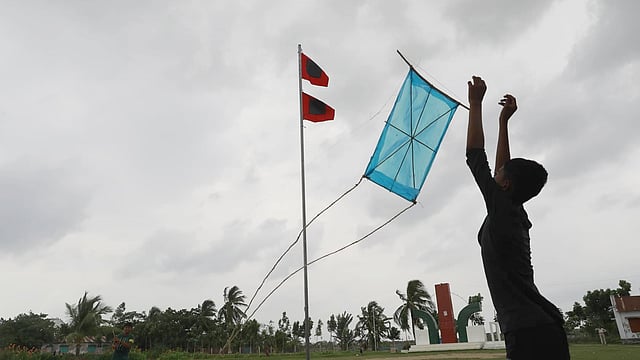 দুর্যোগে বাঁধ মানে না দুরন্ত শৈশব। টাঙানো রয়েছে ঘূর্ণিঝড়ের সতর্কসংকেত। সেখানেই ঘুড়ি ওড়ানোয় মেতেছে শিশুটি। কয়রা উপজেলা পরিষদ চত্বর, কয়রা, খুলনা। ছবি: শুভ্র কান্তি দাশ