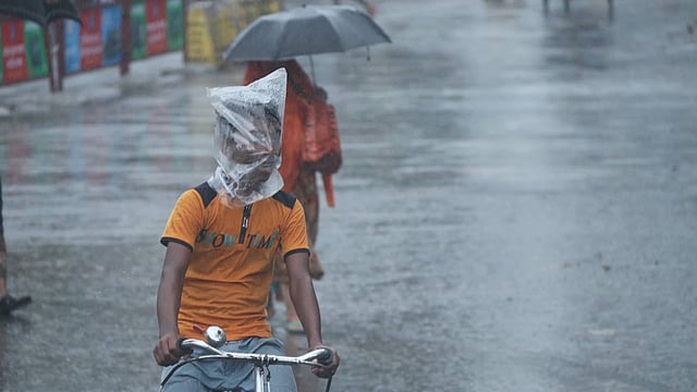 বৃষ্টি থেকে নিজেকে রক্ষার চেষ্টা। সাতমাথা, বগুড়া, ৪ মে। ছবি: সোয়েল রানা