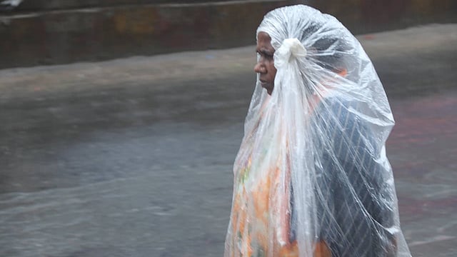 বৃষ্টি থেকে বাঁচতে শরীরে পলিথিন জড়িয়ে নিয়েছেন এক নারী। সাতমাথা, বগুড়া, ৪ মে। ছবি: সোয়েল রানা