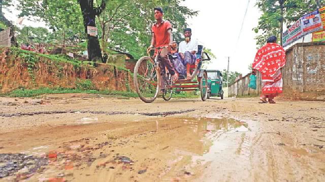 ভাঙাচোরা সড়কে জমে থাকা জল-কাদা মাড়িয়ে চলতে হচ্ছে বাসিন্দাদের। গতকাল দুপুরে সিলেট নগরের টিবিগেট-উত্তর বালুচর সড়কে।   ছবি: প্রথম আলো