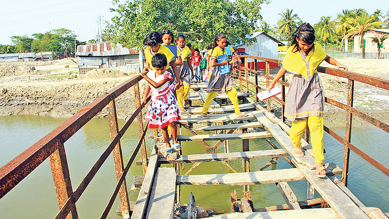 বাগেরহাটের মোংলা বন্দর পৌরসভার মাছমারা খালের ওপরের কাঠের সেতুটি অত্যন্ত জরাজীর্ণ। শিশুরা এটি পার হয় ভয়ে ভয়ে। গত সোমবার মাছমারা গ্রামে।  ছবি: প্রথম আলো