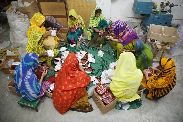 দল বেঁধে টুপির বাড়তি সুতা ছেঁটে ফেলার কাজ করছেন নারীশ্রমিকেরা।