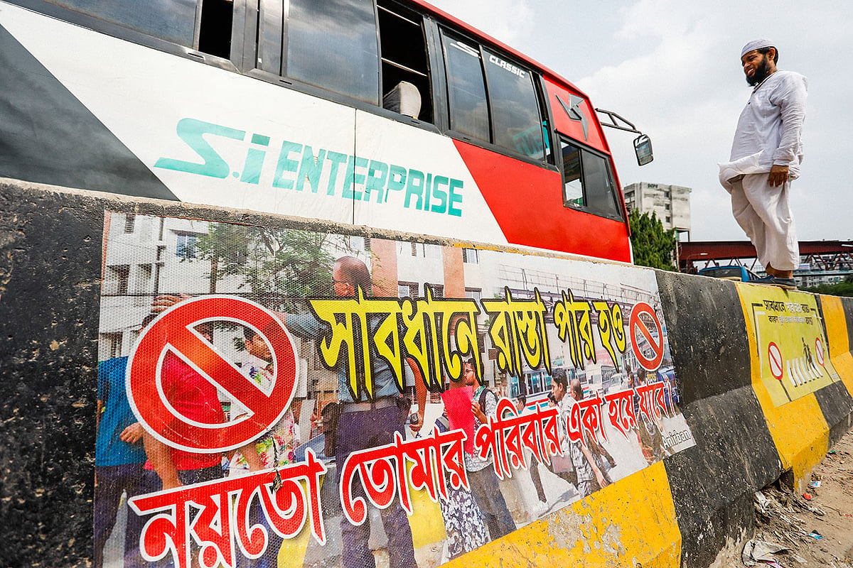 সড়ক বিভাজক টপকে পার হতে গিয়ে হঠাৎ চলে এসেছে বাস। তাই বিভাজকের ওপরেই দাঁড়িয়ে অপেক্ষা করতে হচ্ছে পথচারীকে। অথচ বিভাজকের গায়েই আছে সতর্কবাণী।