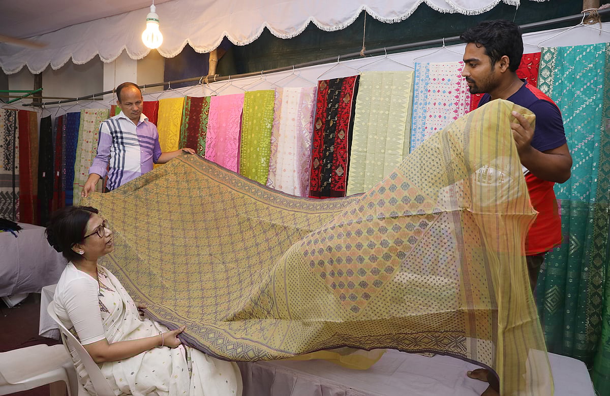 মেলায় শাড়ি পরখ করছেন এক ক্রেতা। ছবি: আবদুস সালাম