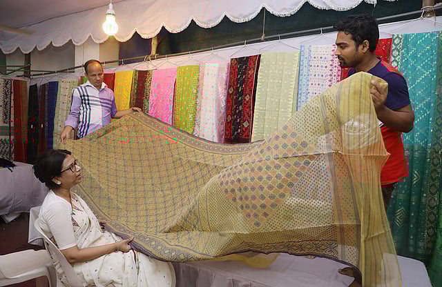 মেলায় শাড়ি পরখ করছেন এক ক্রেতা। ছবি: আবদুস সালাম