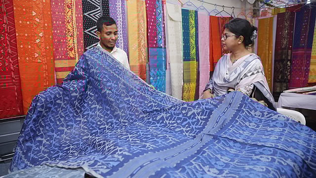 বিক্রেতার সঙ্গে শাড়ির দাম নিয়ে কথা বলছেন এক ক্রেতা।