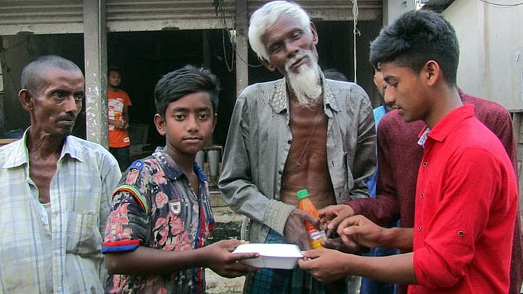 টিফিনের টাকায় শ্রমজীবী, ছিন্নমূল ও ভিক্ষুকদের মধ্যে ইফতার সামগ্রী বিলি করছে শিশুদের হাসি ফাউন্ডেশনের সদস্যরা। হোসেনপুর বাজার, কিশোরগঞ্জ, ২১ মে। ছবি: প্রথম আলো