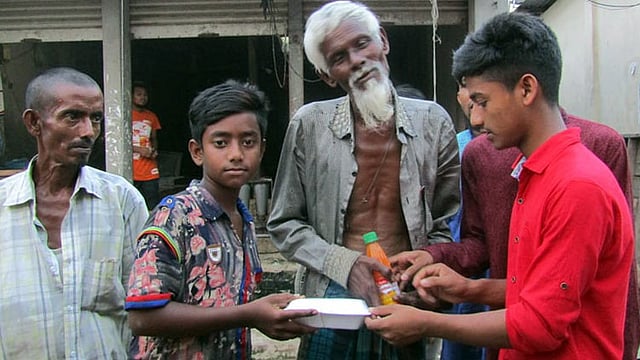 টিফিনের টাকায় শ্রমজীবী, ছিন্নমূল ও ভিক্ষুকদের মধ্যে ইফতার সামগ্রী বিলি করছে শিশুদের হাসি ফাউন্ডেশনের সদস্যরা। হোসেনপুর বাজার, কিশোরগঞ্জ, ২১ মে। ছবি: প্রথম আলো