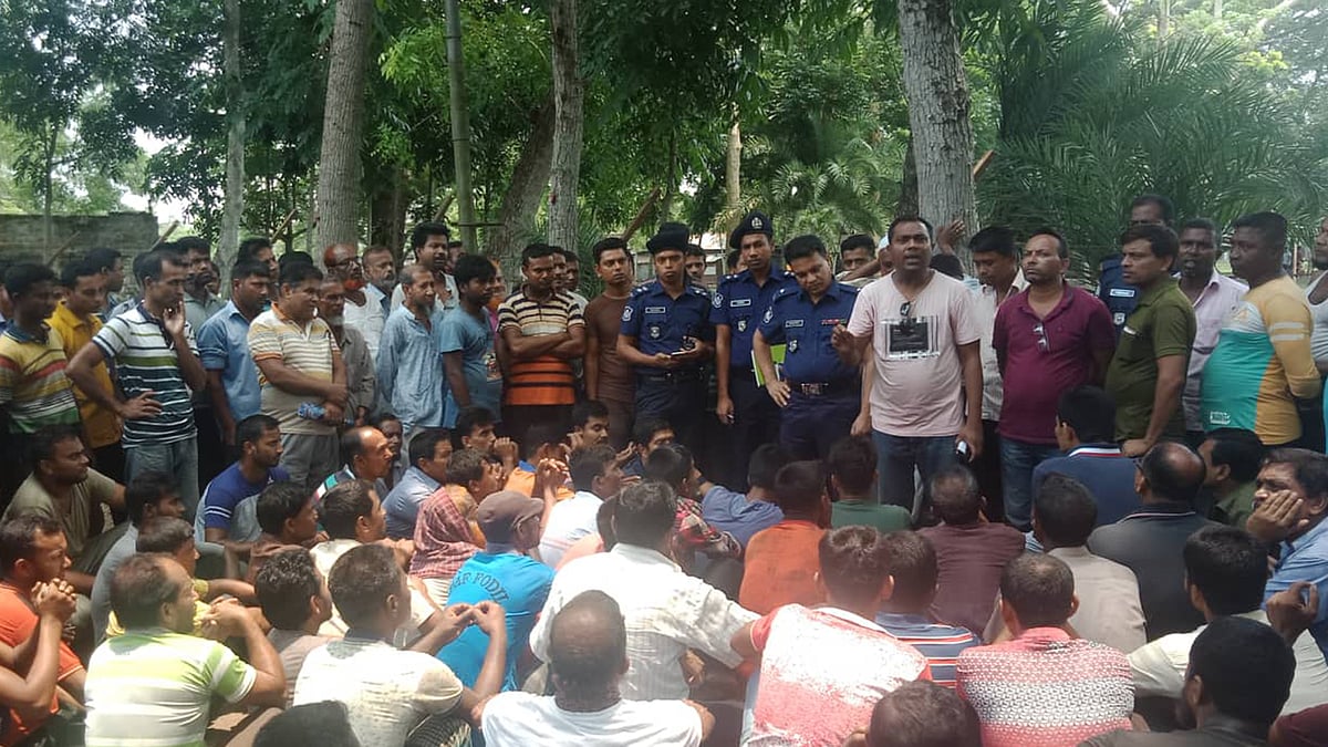 যশোরের অভয়নগরের রাষ্ট্রায়ত্ত যশোর জুট ইন্ডাস্ট্রিজের কর্মকর্তাদের কার্যালয়ের ভেতরে রেখে মূল ফটকে তালা ঝুলিয়ে দিয়ে বাইরে সমাবেশ করেন শ্রমিকেরা। ছবি: মাসুদ আলম