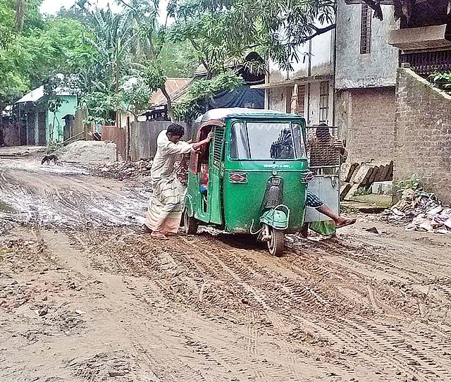 কাদামাটিতে বন্ধ হয়ে গেছে অটোরিকশা। যাত্রীরা ঠেলে গাড়ি সচল করার চেষ্টা করছেন। গত শনিবার ইসলামপুর-দেওয়ানগঞ্জ সড়কের মার্কাস মসজিদের সামনে।  ছবি: প্রথম আলো