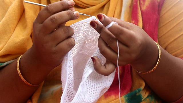 বাড়ির উঠানে বসে টুপি বোনায় ব্যস্ত মাবিয়া খাতুন। ঘরকন্নার কাজের অবসরে টুপি তৈরি করেন তিনি