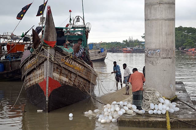 আলীপুর মৎস্যবন্দরে অলস সময় কাটান জেলেরা। ছবি: প্রথম আলো