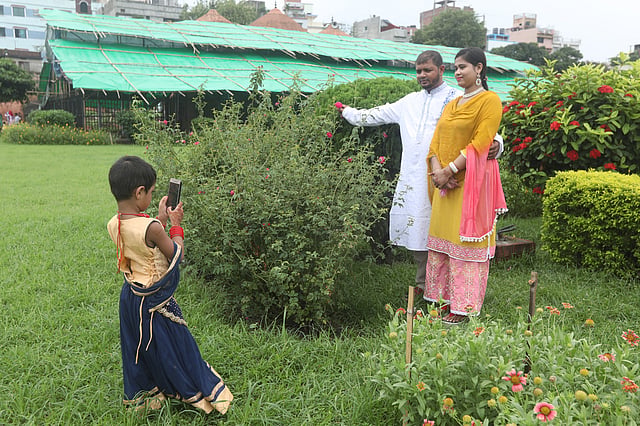 লালবাগ কেল্লা প্রাঙ্গণে মা-বাবার ছবি তুলে দিচ্ছে শিশুটি। ছবি: সাইফুল ইসলাম