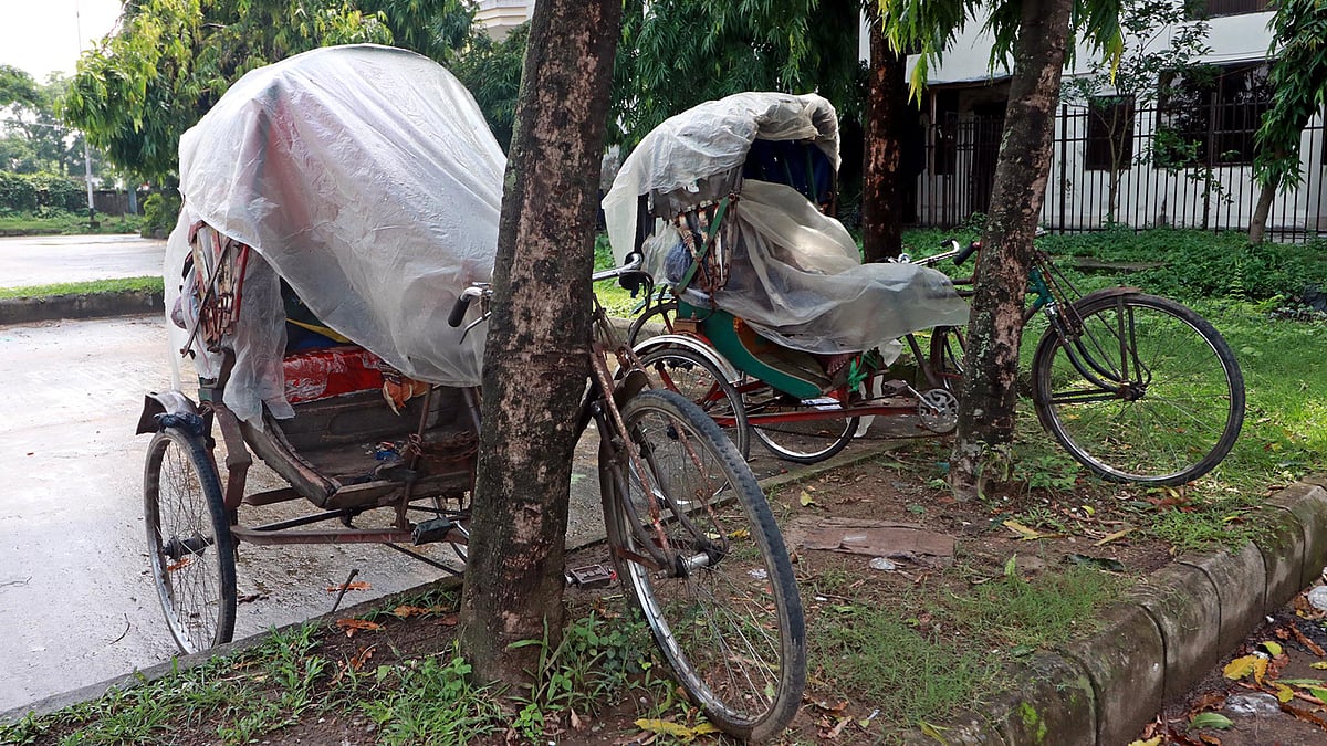 ক্লান্ত শরীর নিয়ে রিকশায় ঘুমিয়ে পড়েন চালক। হঠাৎ বৃষ্টিতে যাতে বিড়ম্বনায় না পড়েন, সে জন্য পলিথিন দিয়ে মুড়িয়ে নিয়েছেন রিকশা। রেলওয়ে স্টেশন এলাকা, সিলেট, ৯ জুন। ছবি: আনিস মাহমুদ।