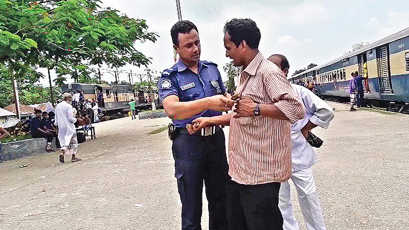 রাজবাড়ীতে আন্তনগর ট্রেন মধুমতি এক্সপ্রেসের যাত্রীদের কাছ থেকে অবৈধভাবে টাকা নিচ্ছে জিআরপি পুলিশ। কালুখালী রেলস্টেশনে গত রোববার দুপুরে। প্রথম আলো