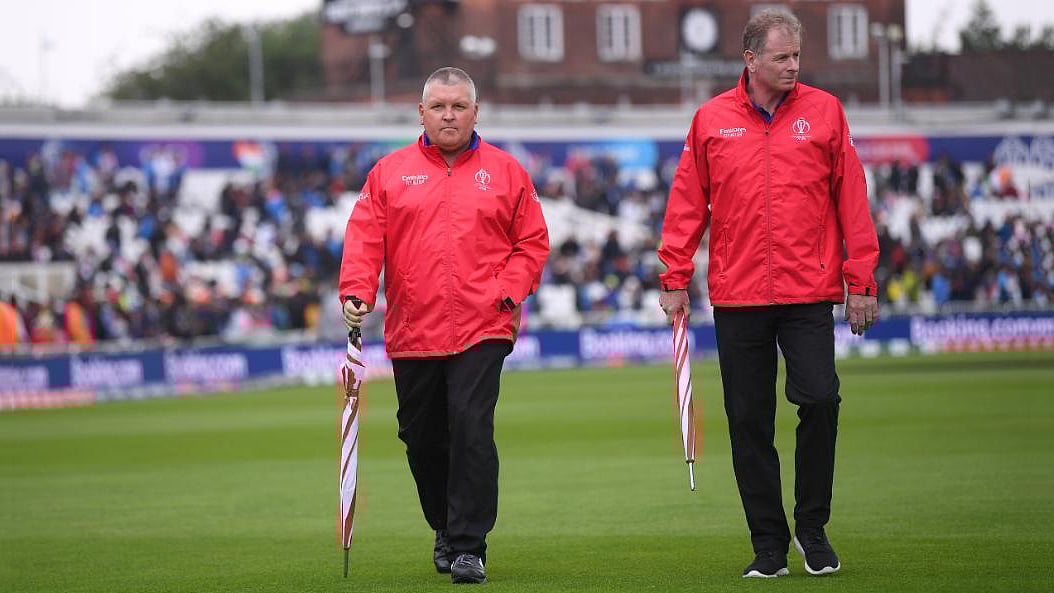 এবার বিশ্বকাপ উপলক্ষে দেশি বিদেশি সব আম্পায়ারই নিপাট ব্রিটিশ ভদ্রলোক বনে গেছেন। হাতে ছাতা ছাড়া তাঁদের দেখাই মিলছে না। তাদেরই-বা দোষ কী? এবারের বিশ্বকাপে বৃষ্টি যে কাউকে ছেড়ে কথা বলছে না! ছবি: আইসিসি