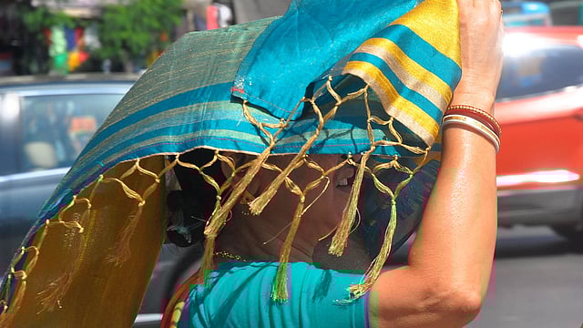 তাপ থেকে রেহাই পেতে শাড়ির আঁচলে মাথা ঢেকেছেন এই নারী। ছবি: ভাস্কর মুখার্জি