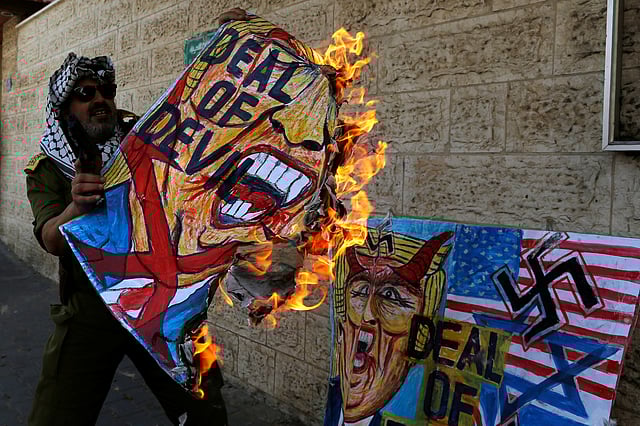 মার্কিন প্রেসিডেন্ট ডোনাল্ড ট্রাম্পের কুশপুত্তলিকা দাহ করছেন এক ফিলিস্তিনি। গাজা সিটি, ২৪ জুন। ছবি: রয়টার্স