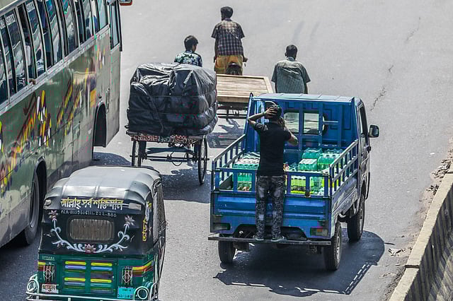 মহাসড়কে ঝুঁকি নিয়ে পিকআপ ভ্যানের পেছনের অংশে দাঁড়িয়ে যাচ্ছেন এক ব্যক্তি। সামান্য একটু ভুলে ঘটতে পারে জীবননাশের মতো দুর্ঘটনা। দনিয়া, ঢাকা, ২৪ জুন। ছবি: দীপু মালাকার