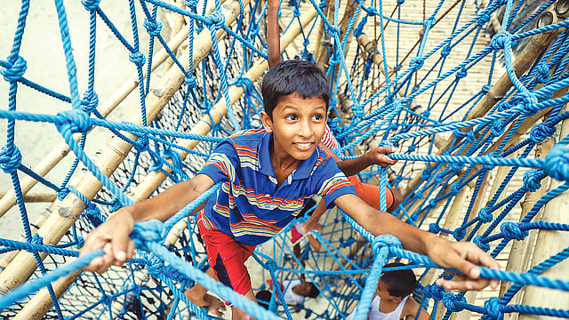 বাঁশের খেলাঘরে দড়ির জাল বেয়ে ওঠানামা করছে শিশুরা। মোহাম্মদপুরের ওয়াসিপুর এলাকায়।  ছবি: প্রথম আলো